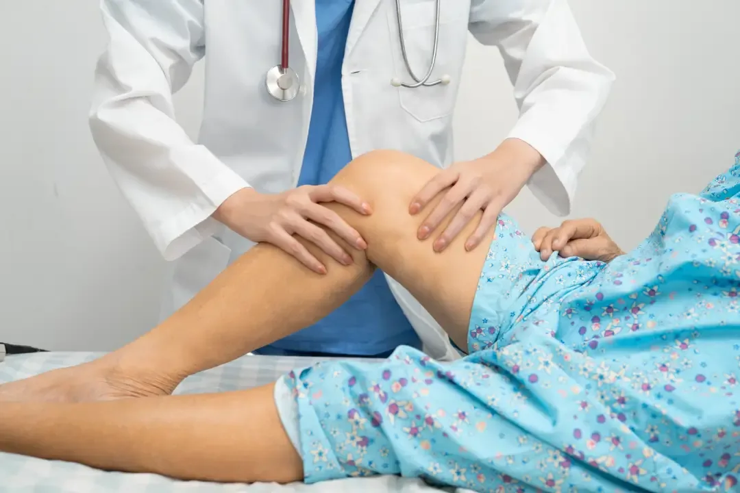 Doctor in white coat examining a patient's knee during office visit