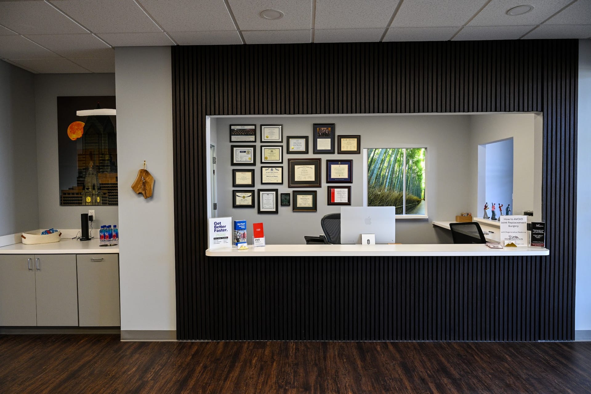 Modern medical office reception desk with diplomas and credentials on dark wall