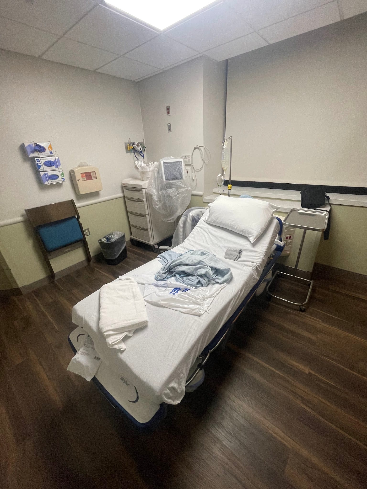 Clean hospital bed in a medical treatment room with IV stand and equipment