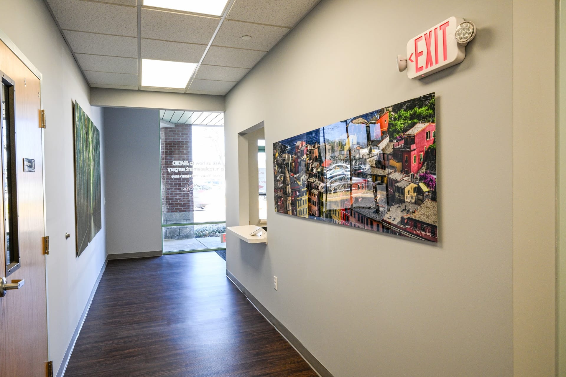 Bright office hallway with colorful cityscape wall art and exit sign