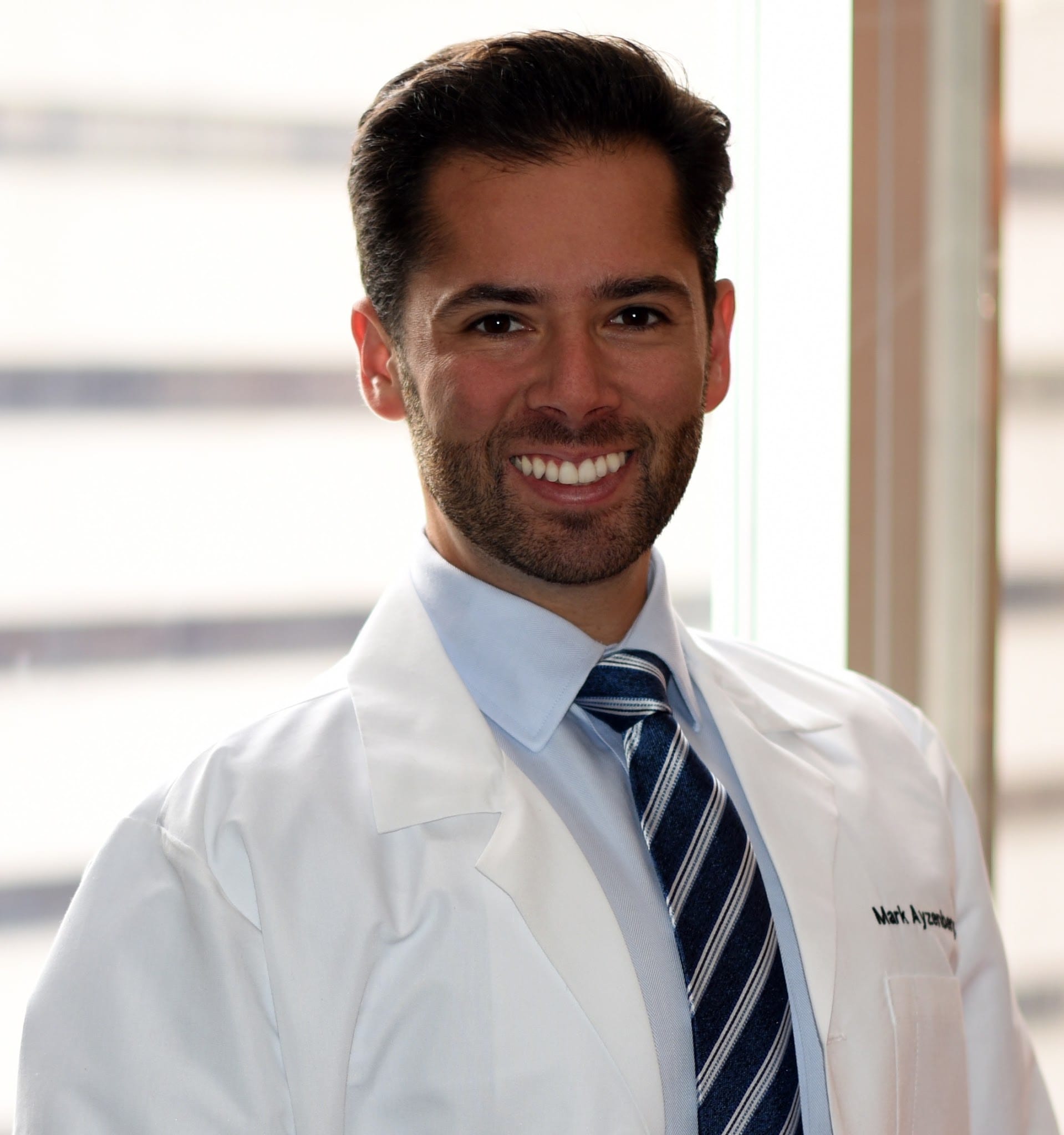 Dr. Mark Ayzenberg smiling in white coat and striped tie